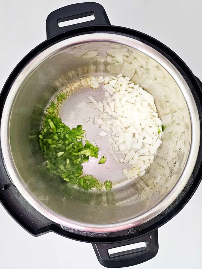Onions, green bell peppers and garlic sautéing in an Instant Pot.
