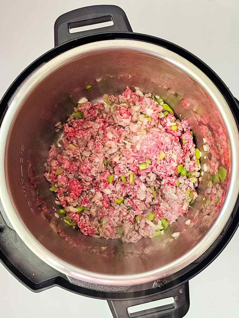Ground beef mixed with onions and bell peppers in an Instant Pot.