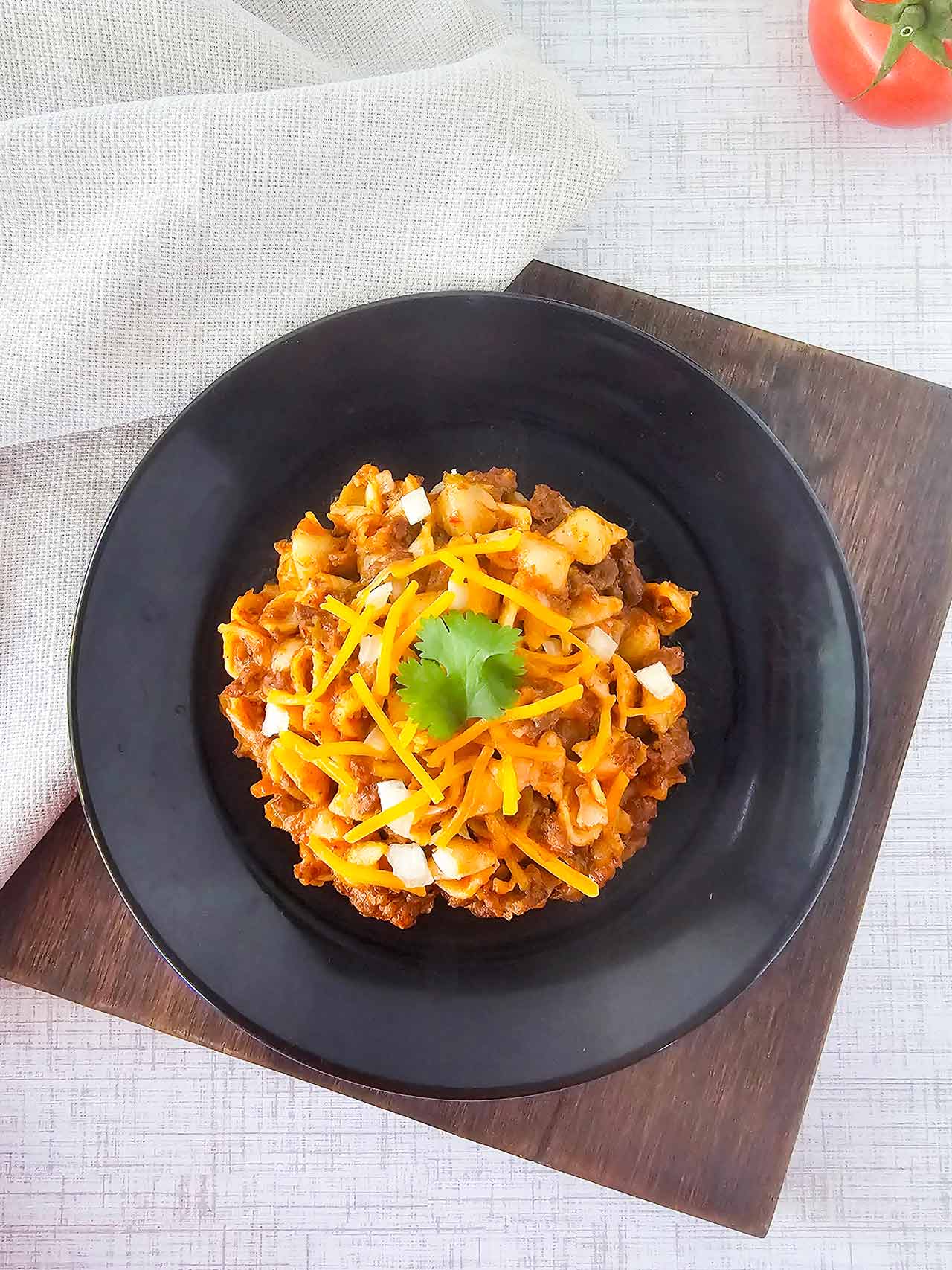 A serving of taco casserole on a black plate. Overhead focus.