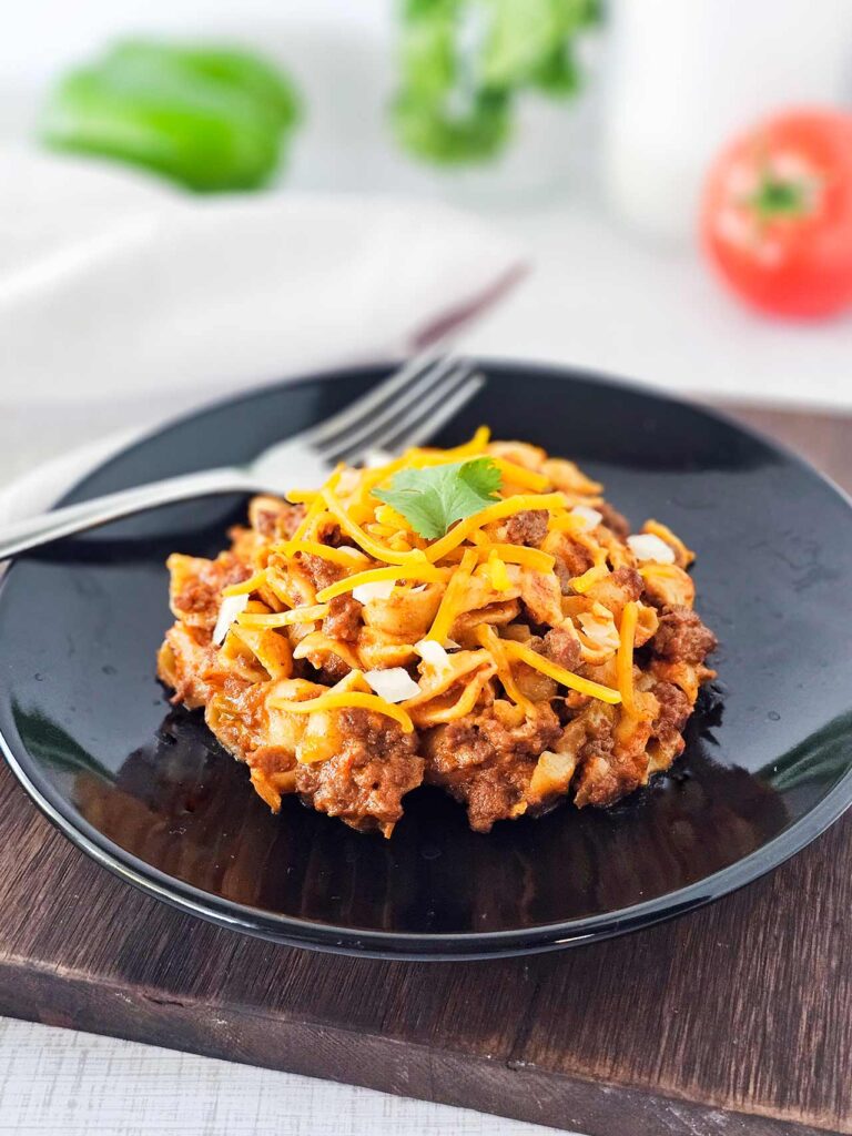 A serving of taco casserole on a black plate with a fork.