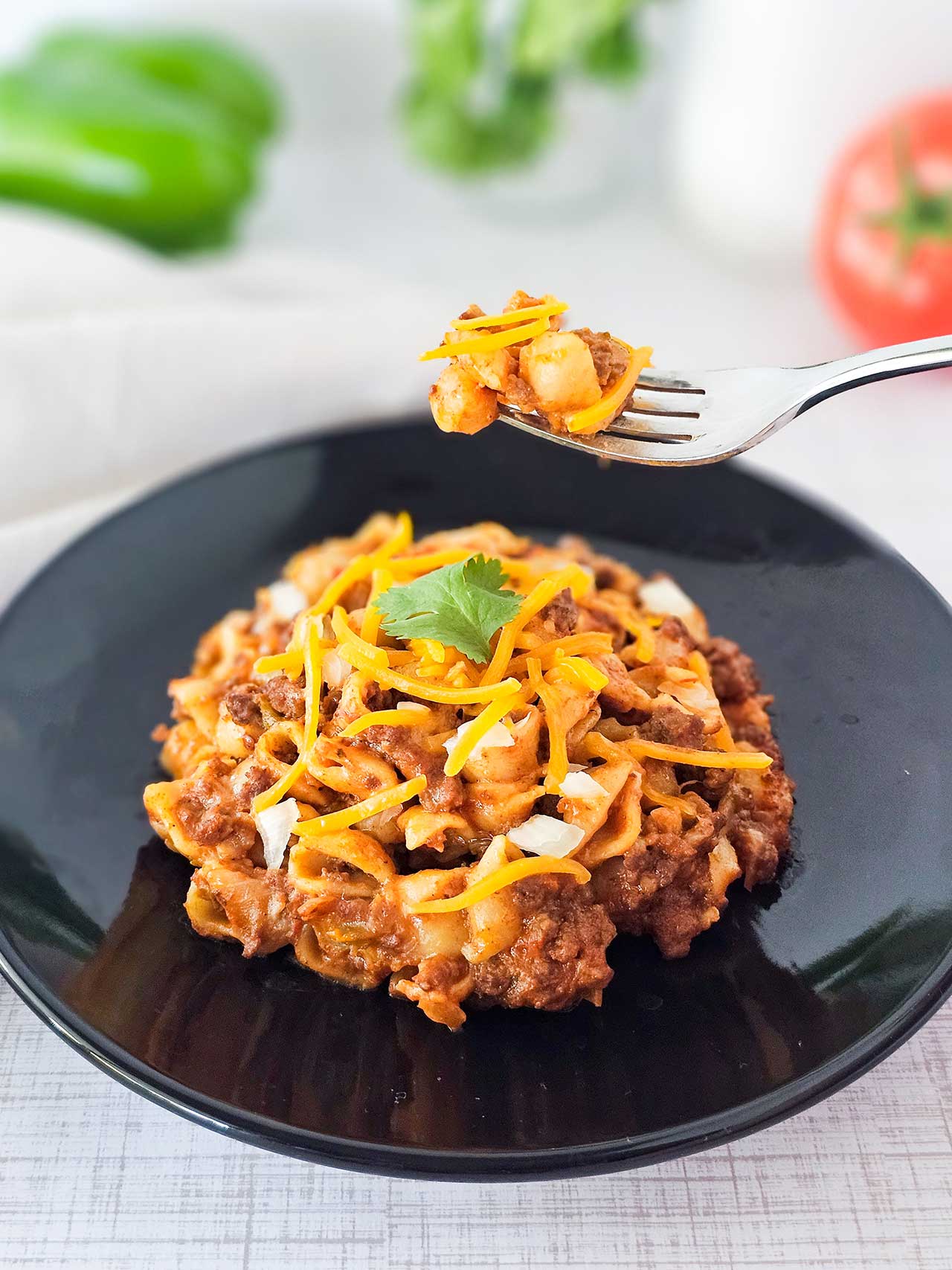A fork lifts up a bit of taco casserole from a black plate.