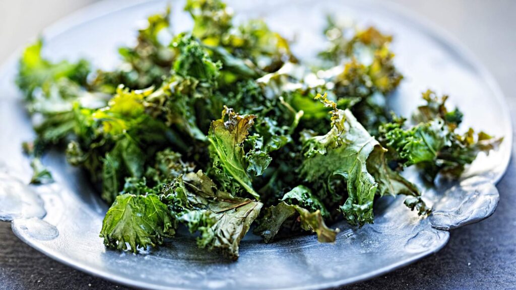 Kale chips laying on a blue plate.