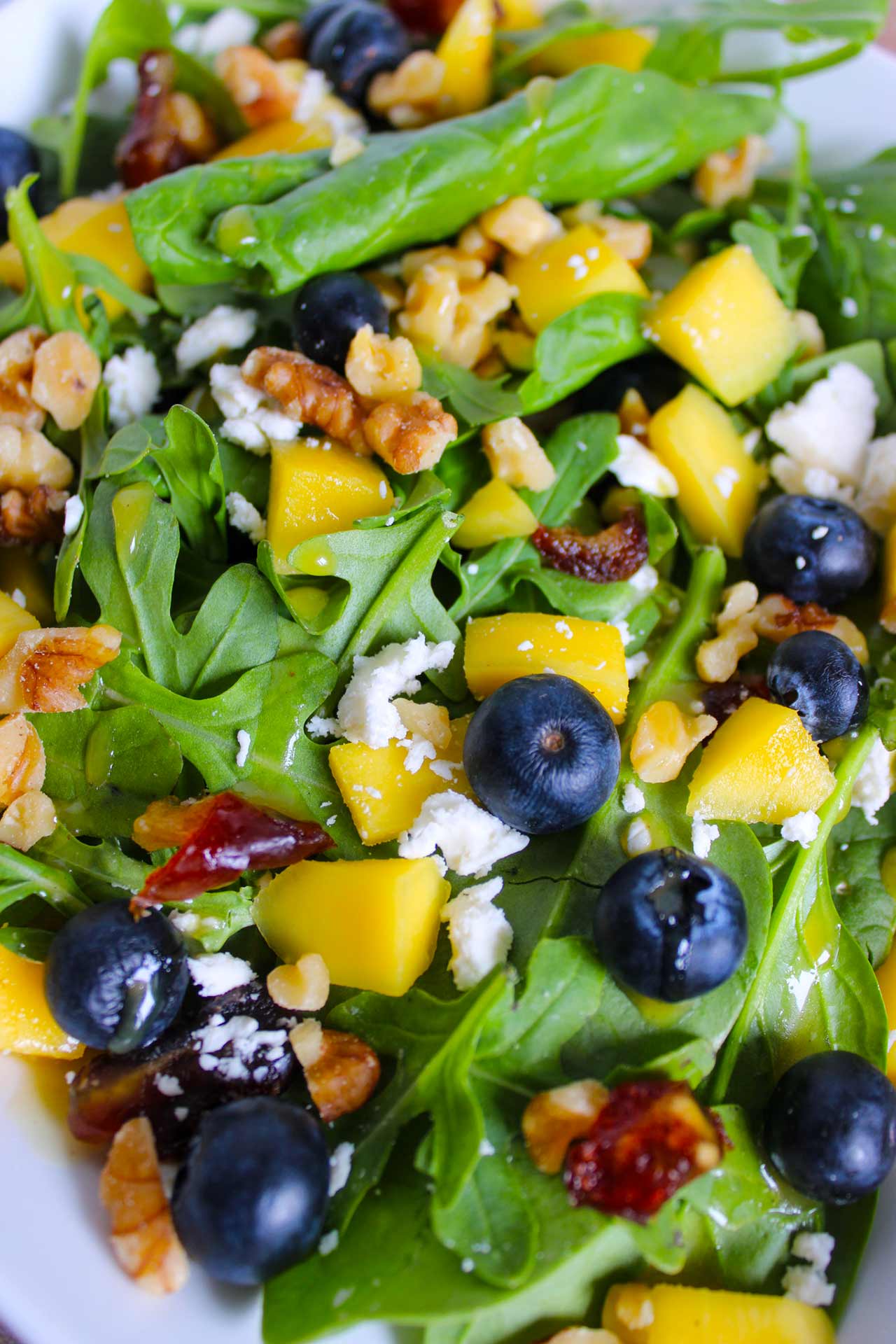 An overhead view of a Mango Blueberry Salad on a white plate.