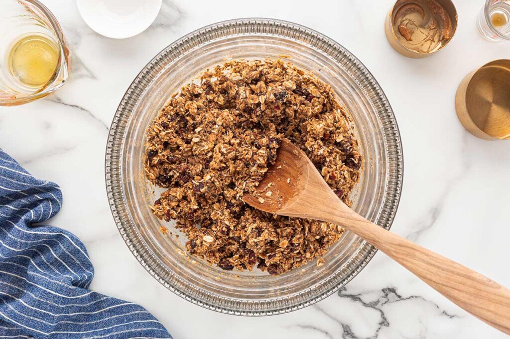 No-bake cookie ingredients mixed in a mixing bowl with a wooden spoon.