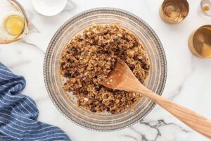 No-bake cookie ingredients mixed in a mixing bowl with a wooden spoon.