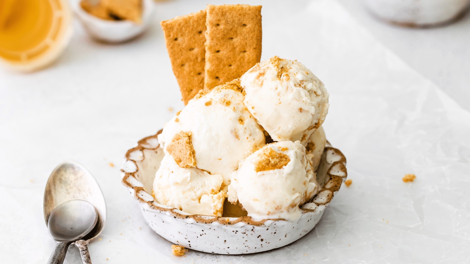 A bowl with several scoops of no-churn cheesecake ice cream with some graham cracker stick into them for garnish.