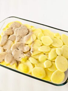 A second layer of potatoes and sauce in a casserole dish.