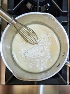 Flour added to milk and butter in a pot.