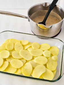 A single layer of sliced potatoes layered in a casserole dish.