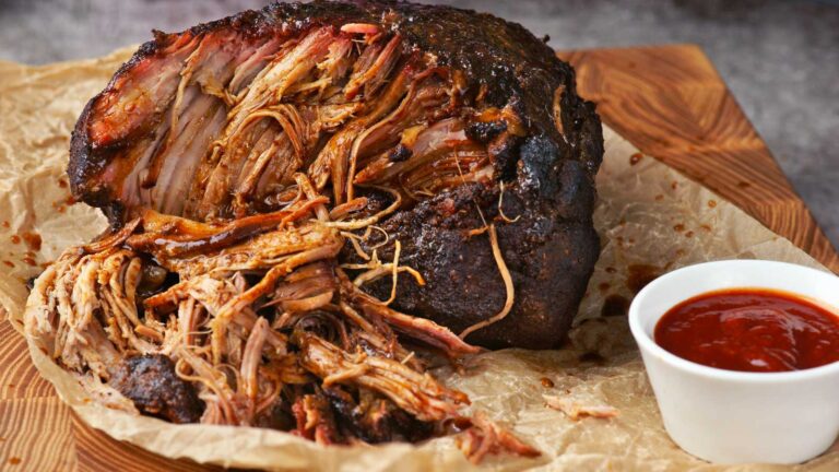 a piece of pulled pork with sauce on parchment paper.