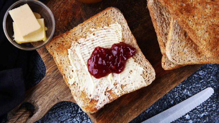 Toasted bread with homemade raspberry butter and on rustic table served with butter for breakfast or brunch.