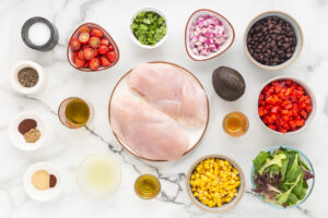 Southwest Salad Recipe ingredients on a white marble surface in individual bowls.
