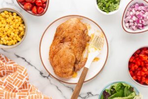 A chicken breast brushed with seasoning.