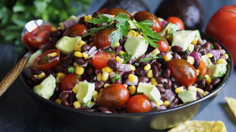 Homemade Mexican black bean and corn salad or Texas caviar salad with lime dressing, Served with tortilla chips and fresh ingredients. Blurred background.