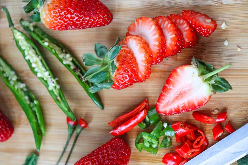 Prepped Spicy Strawberry Mocktail ingredients on a wood cutting board.