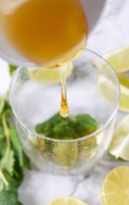 Adding sweetener to mint leaves in glass.