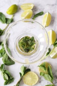 Muddled mint leaves in the bottom of a glass.