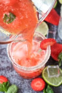Pouring Strawberry Mojito Mocktail into a glass.