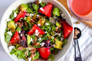 An overhead view of a white bowl filled with Strawberry Pistachio Goat Cheese Salad.