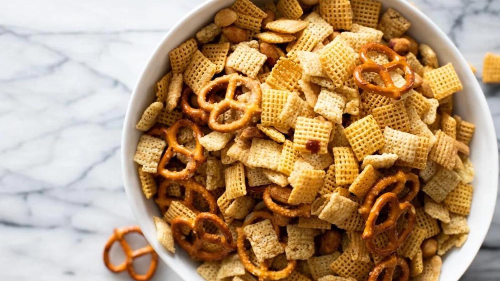 An overhead view of a white bowl filled with sweet and salty Chex mix.