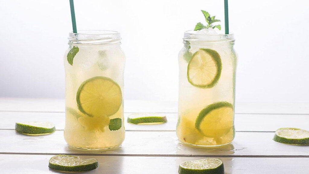 Two glasses of mint pineapple ginger mojitos on a white background.