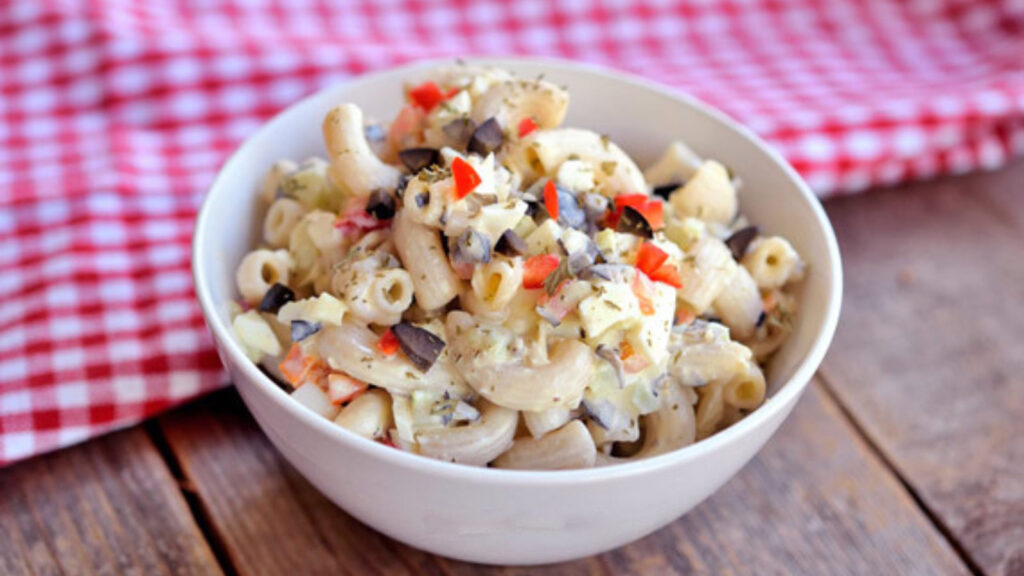 Traditional Macaroni Salad in a white bowl on a wood table.