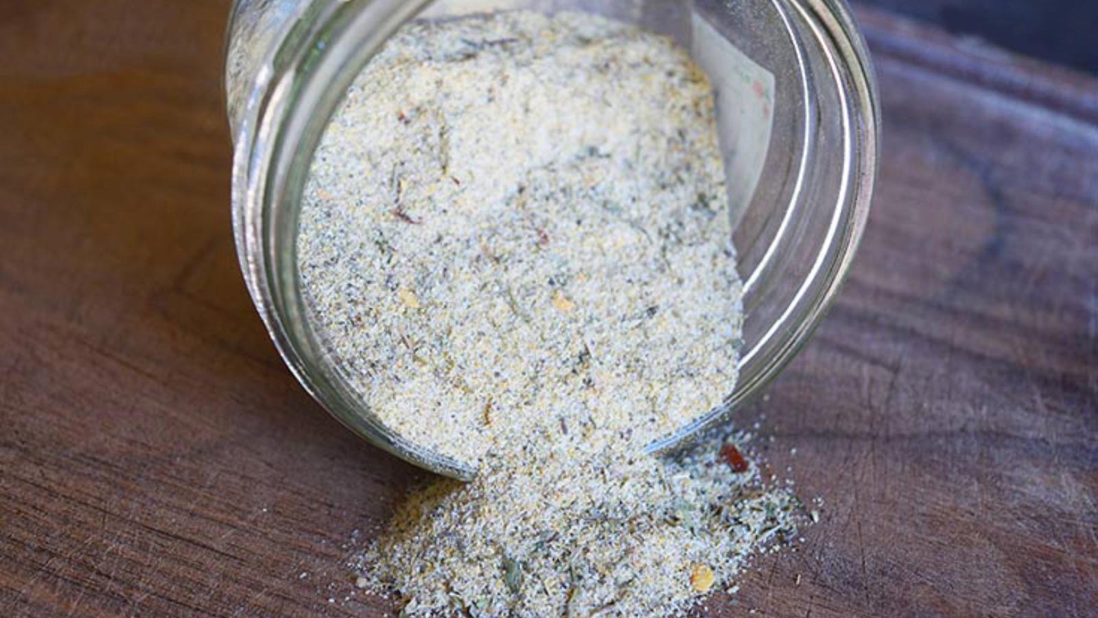 A side view of the finished Tuscan Seasoning Recipe in a tipped over jar.