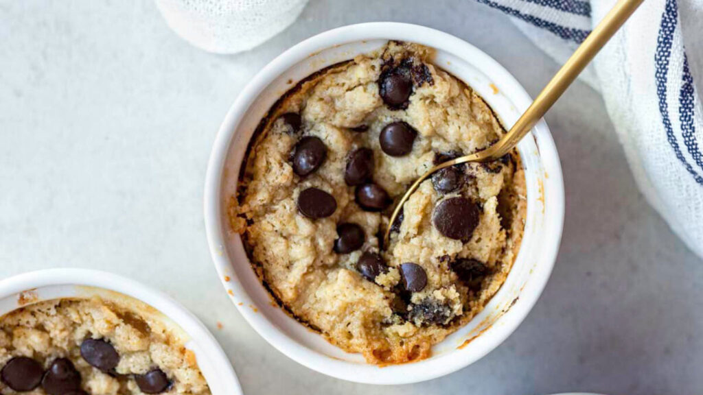 An overhead view of two white bowls filled with baked cookie dough.