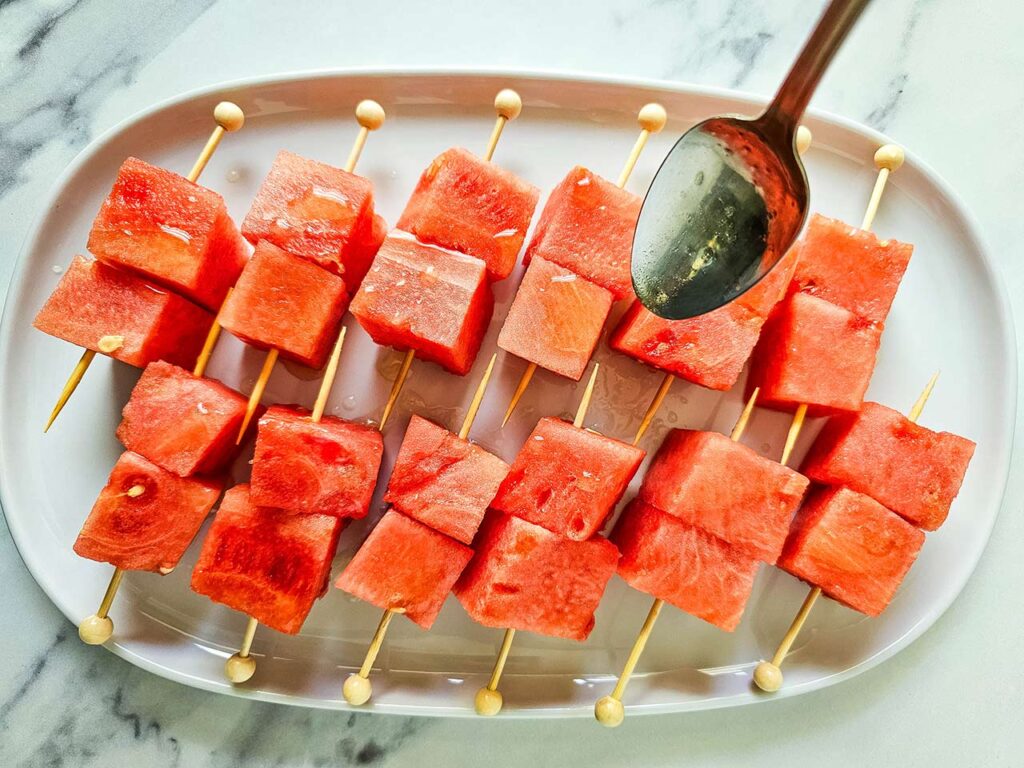 Drizzling oil over Watermelon Feta Skewers.