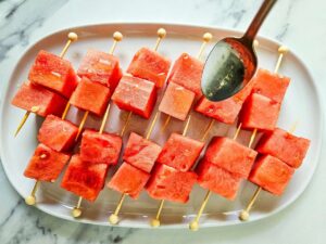 Drizzling oil over Watermelon Feta Skewers.
