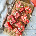 Watermelon Feta Skewers laying on a parchment lined cutting board.
