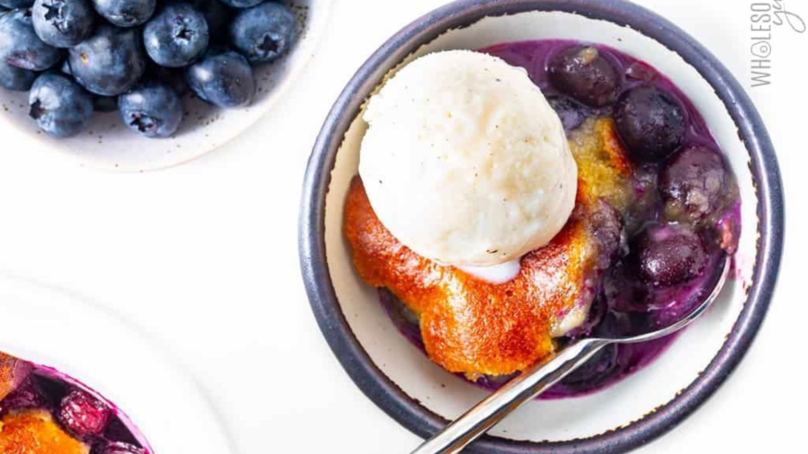 And overhead view of a bowl with blueberry cobbler and a scoop of vanilla ice cream in it.