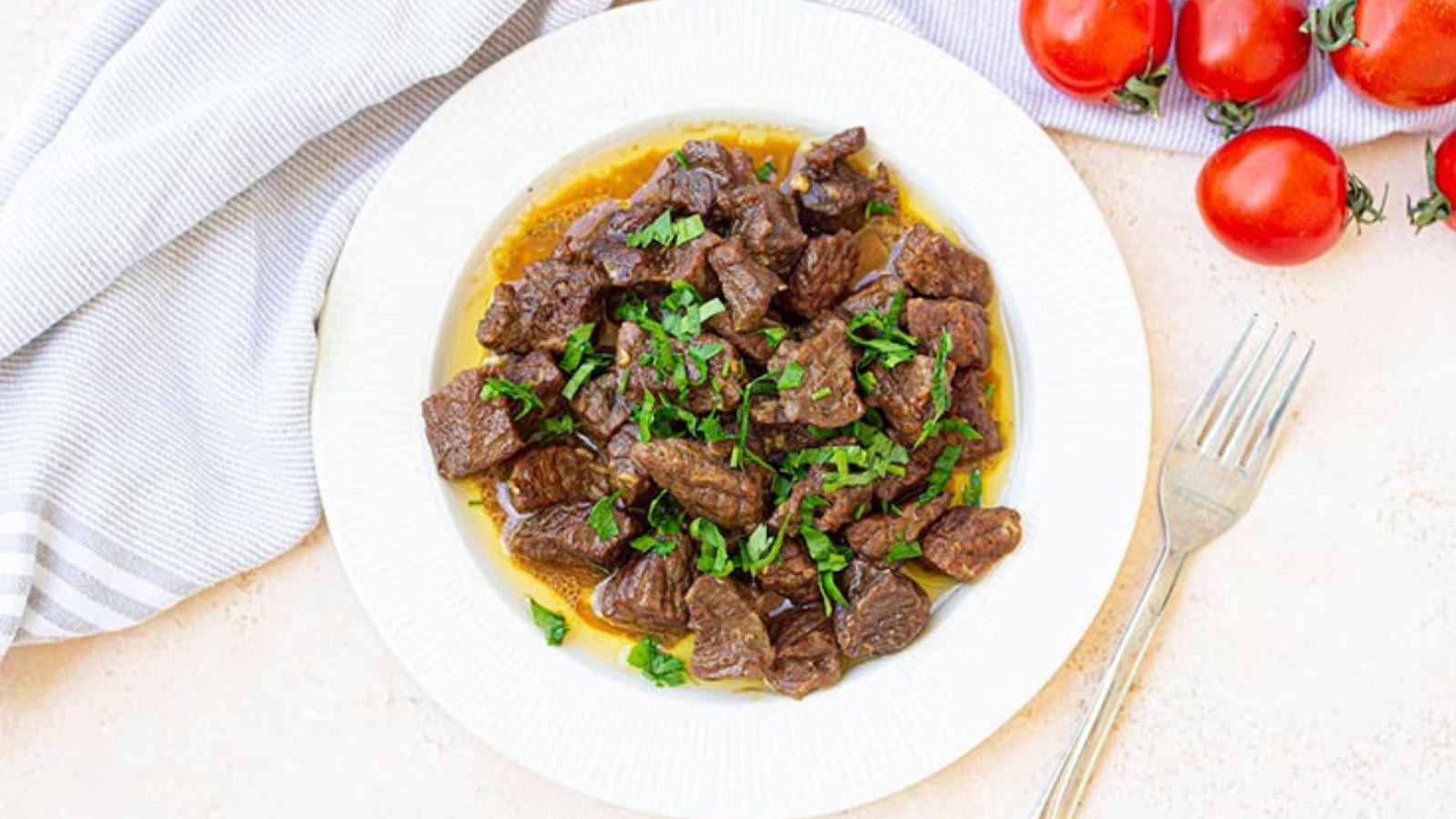 A white plate filled with Instant Pot Garlic Butter Steak Bites.