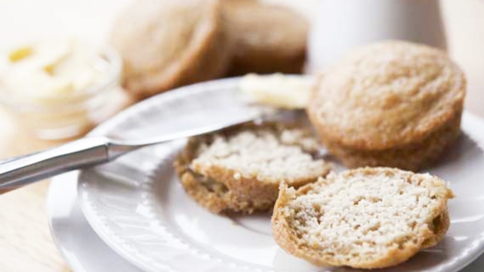A plate holds two low carb muffins. One whole, and one cut in half for spreading butter.