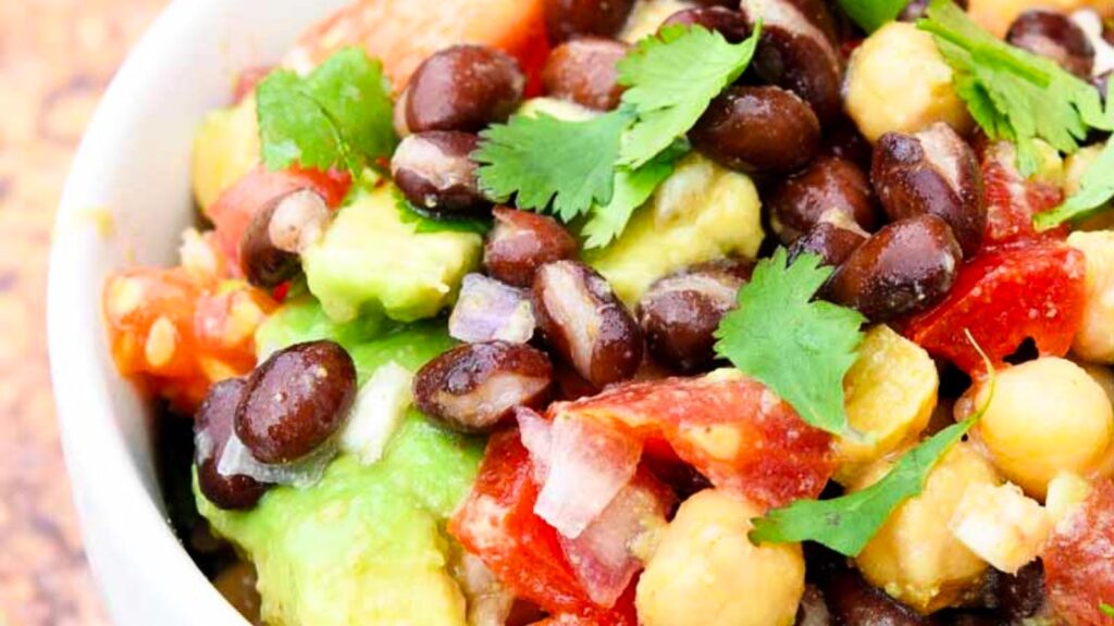 An up close view of a white bowl filled with chickpea black bean salad.