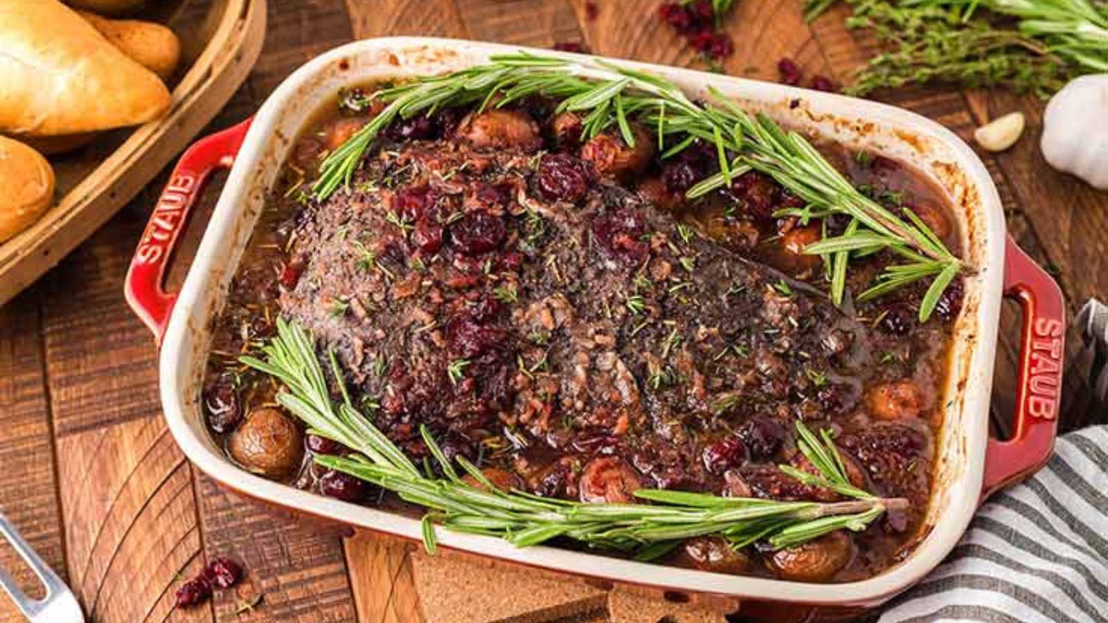A casserole dish filled with cranberry holiday beef brisket and topped with fresh sprigs of rosemary.