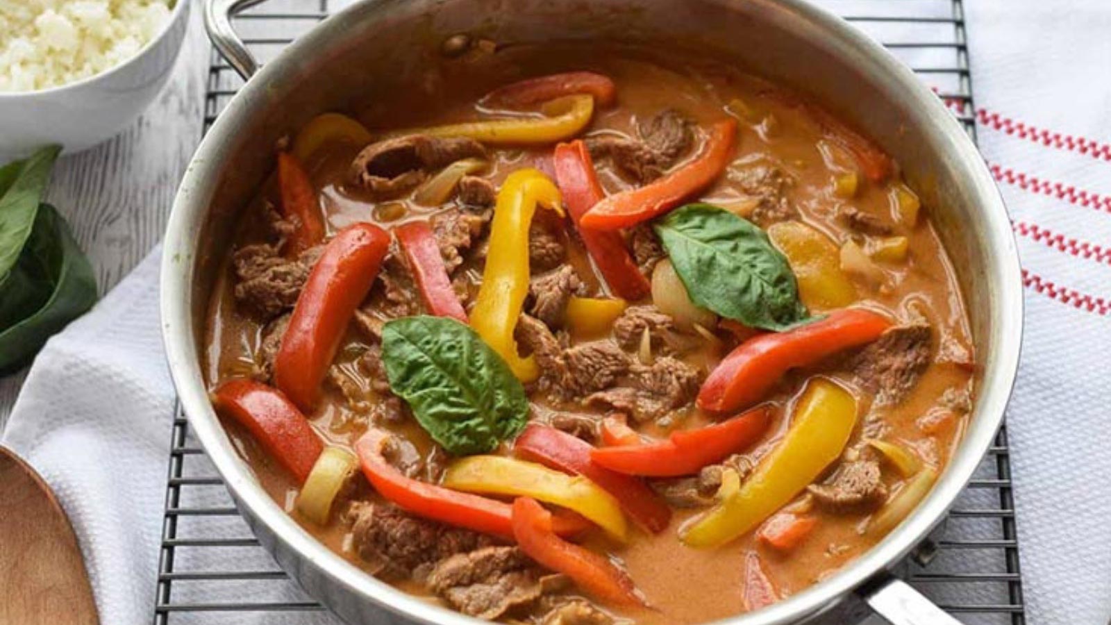 A skillet filled with beef curry and bell peppers strips.