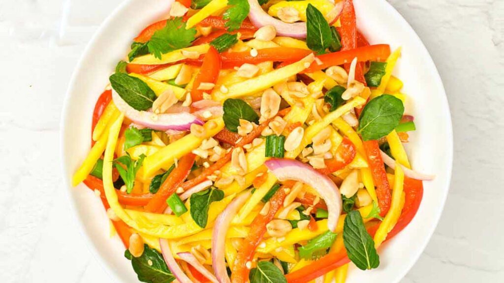 An overhead view of a white plate on a white surface holding Mango Salad.