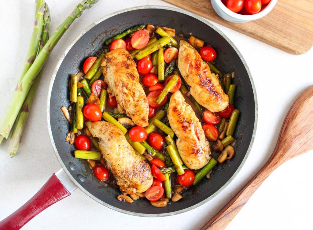 Chicken and veggies cooked and sitting in a skillet.