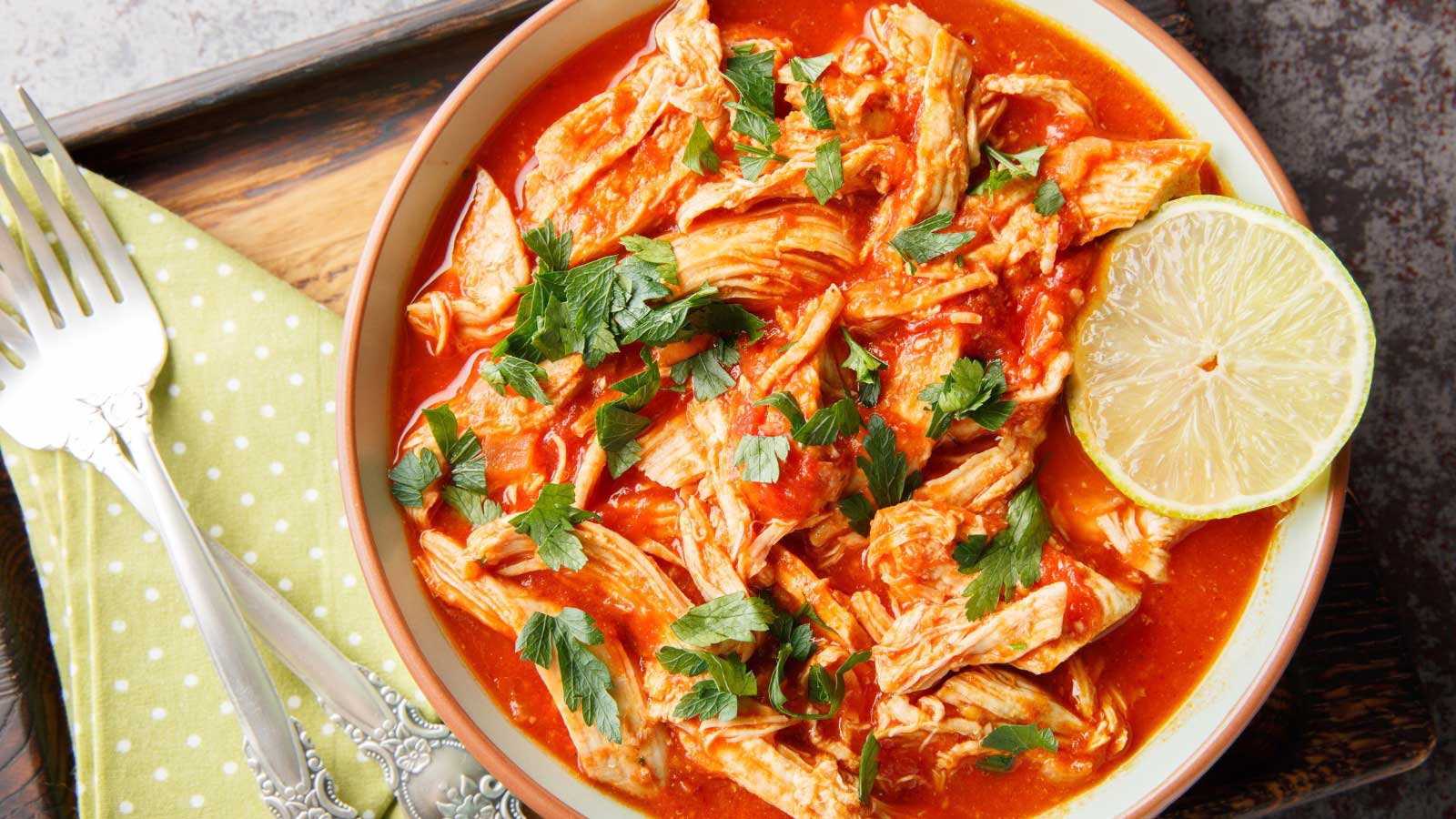 Mexican Baked shredded Chicken and tomato salsa close-up in a bowl on a wooden board. Horizontal top view from above.