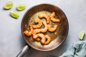 Shrimp sautéing in a skillet with oil.