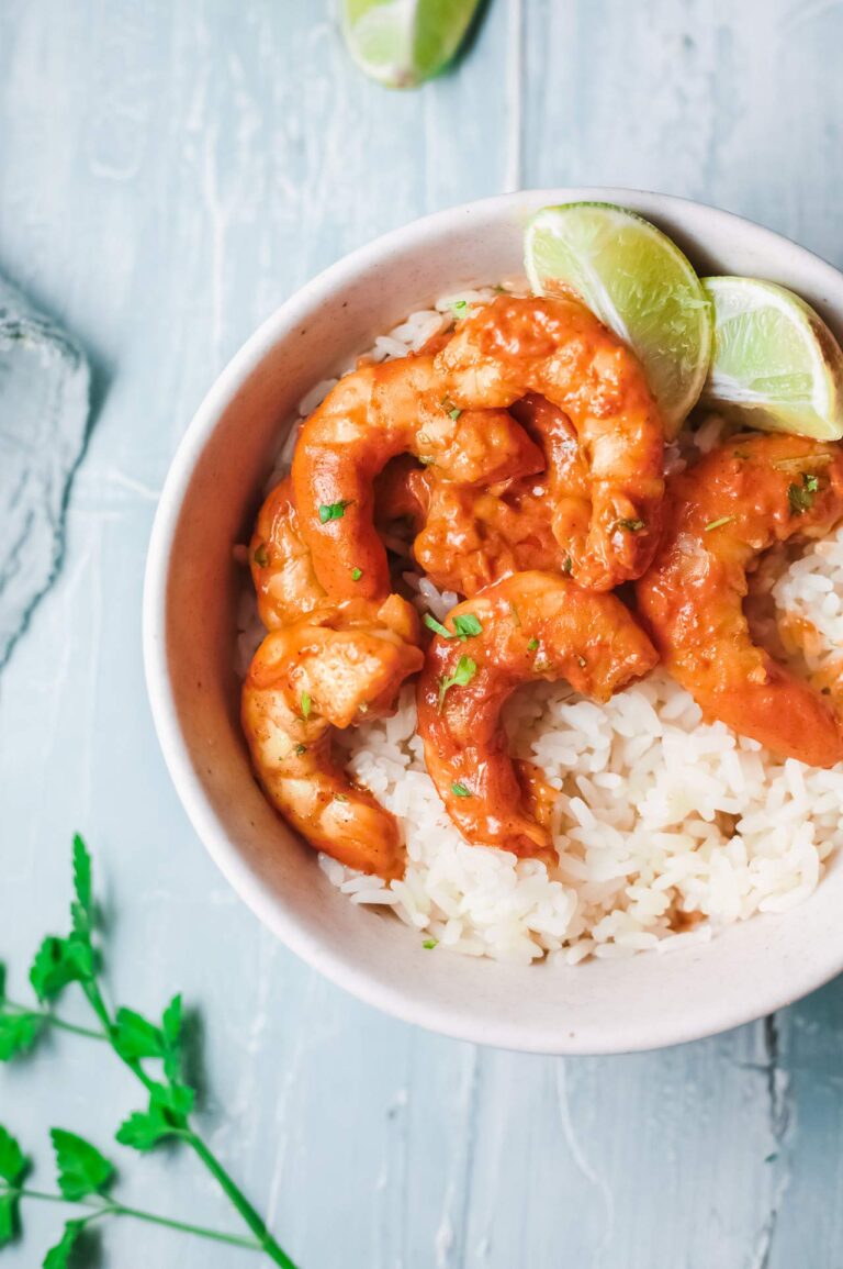 Overhead focus. White bowl sits to the right showing partial view of being filled with rice and shrimp curry.