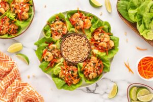 Overhead view of a platter of Thai Shrimp Lettuce Wraps on a white table.