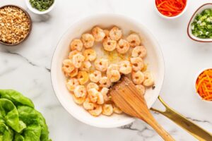 Shrimp added to garlic and ginger in a skillet.