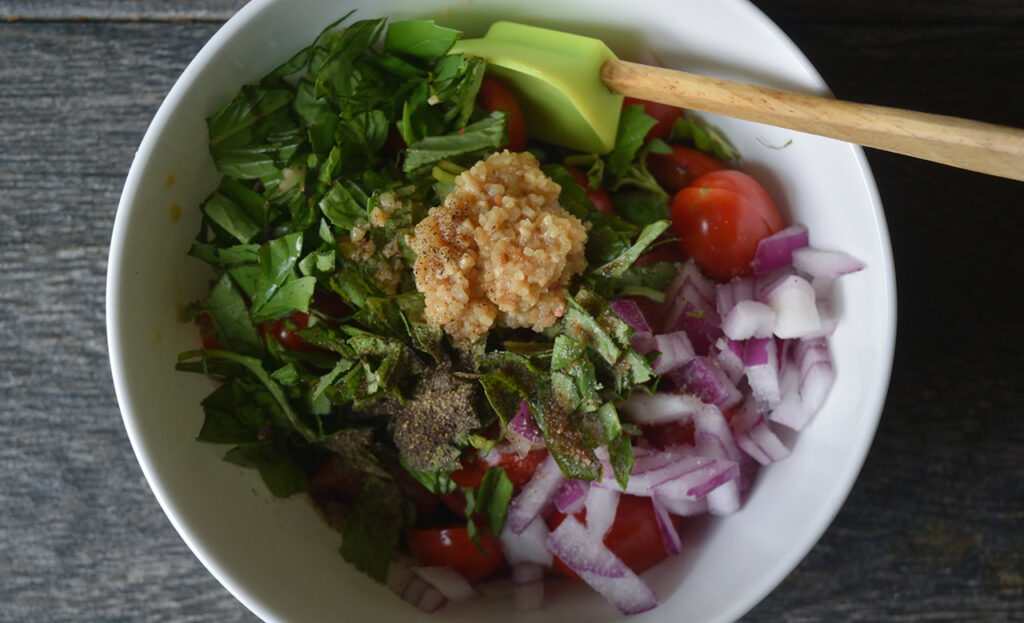 Fresh bruschetta topping ingredients in a white mixing bowl.