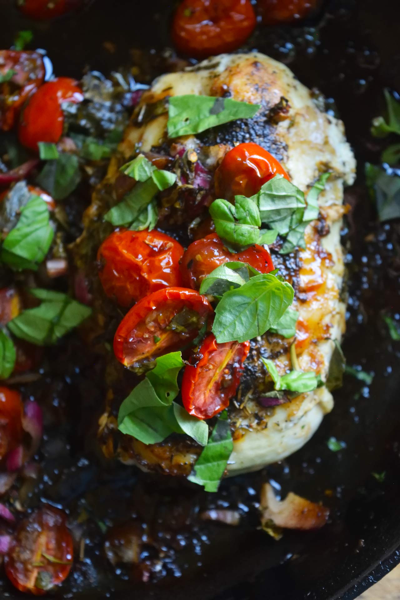 A closeup of a single piece of bruschetta chicken in a skillet.