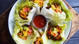 An overhead view of a round platter filled with California Lettuce Wraps with a small bowl of salsa in the middle.
