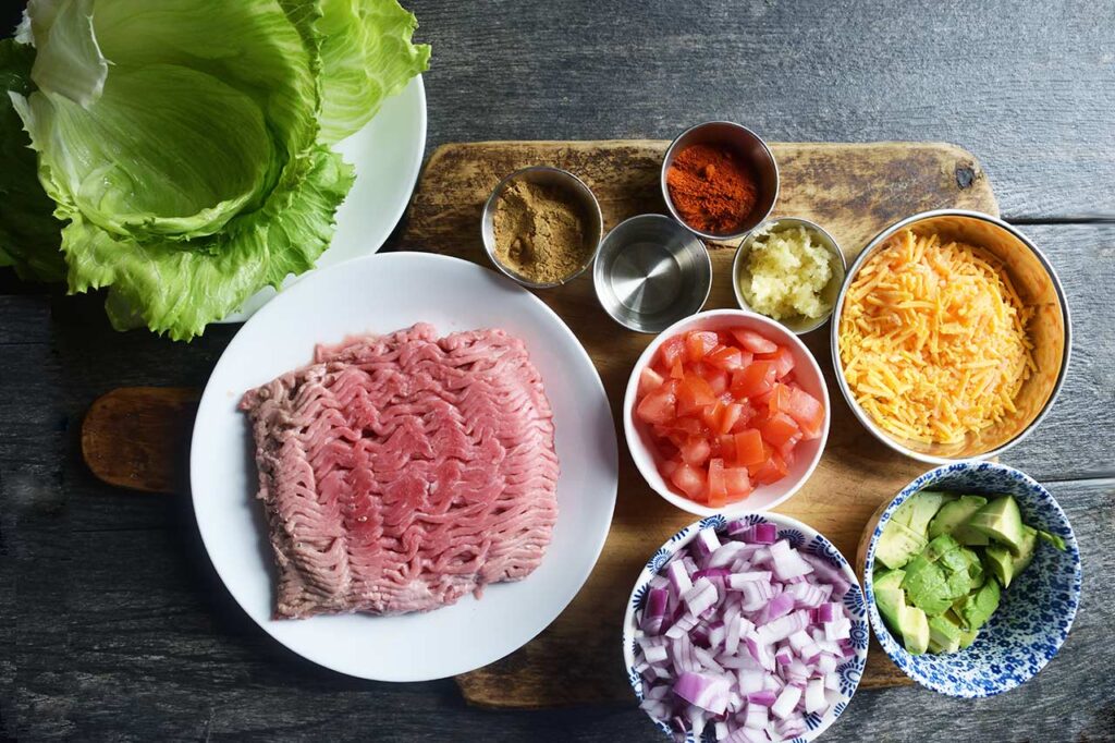 Taco Lettuce Wrap recipe ingredients gathered on a wood cutting board.