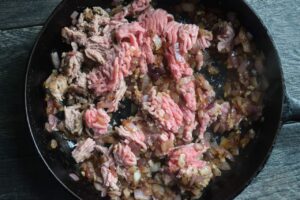 Ground turkey, onions, and garlic, cooking in a skillet.