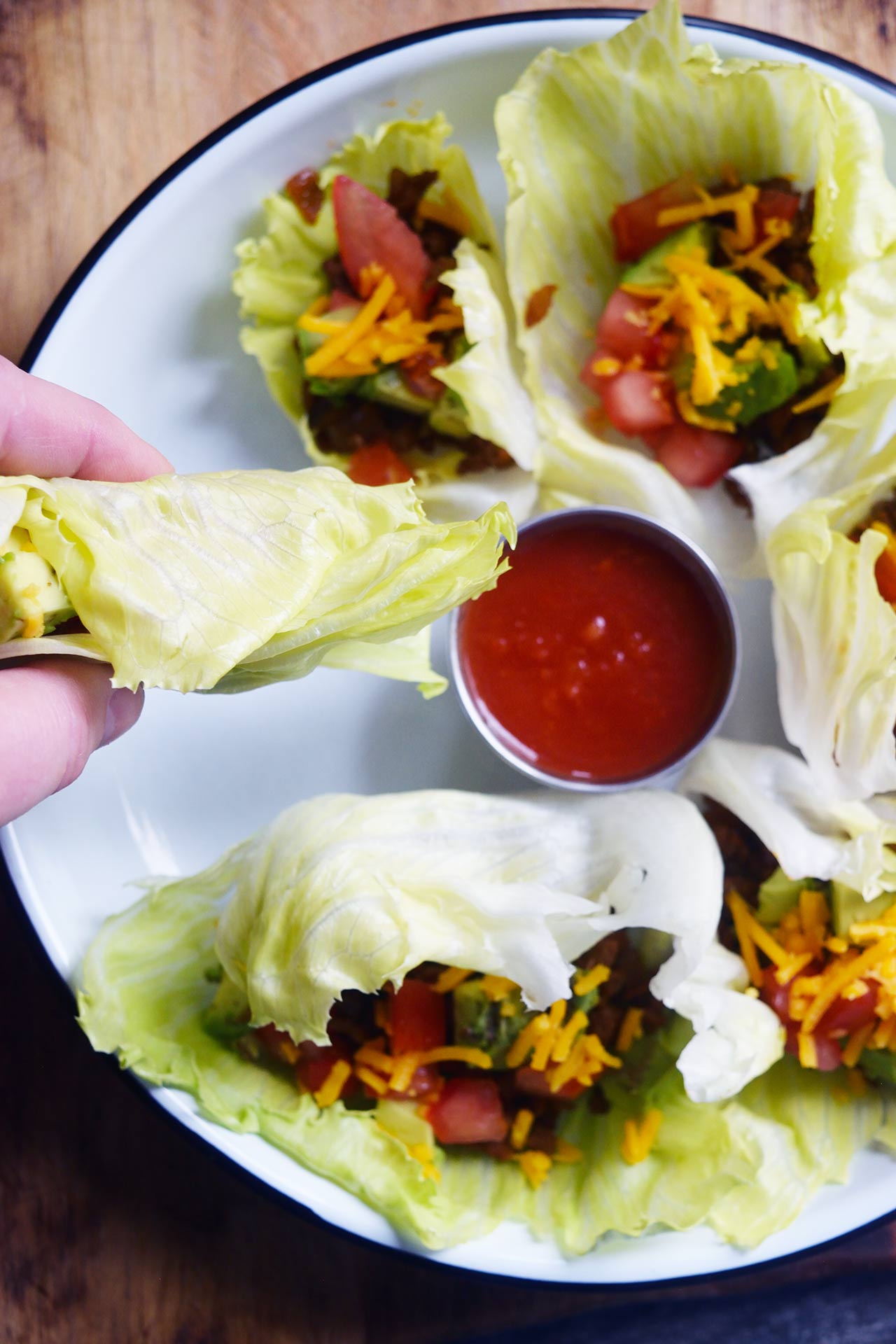 A Taco Lettuce Wrap being dipped in a small bowl of salsa.
